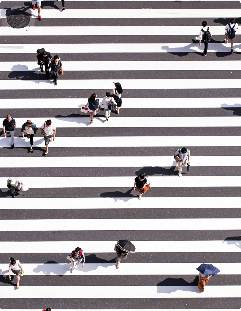 People crossing a striped pedestrian crosswalk.